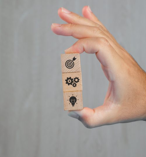 business concept grey table side view hand holding wooden cubes with icons